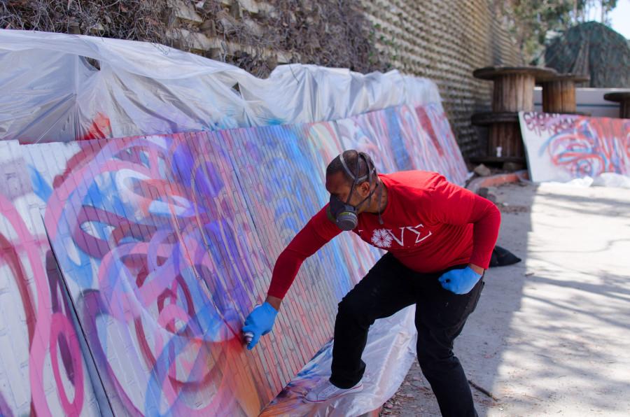 Chor Boogie works on his latest installment “Bloom Bash” for the San Diego Museum of Art. He repeatedly spray paints a blend of floral colors onto several large canvases on April 7. Photo credit: Richard Lomibao