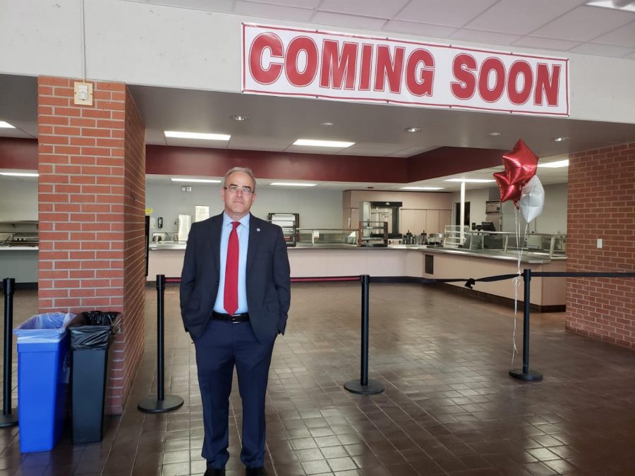 Chris Manis standing in front of a coming soon sign hanging over a closed section of the cafeteria.