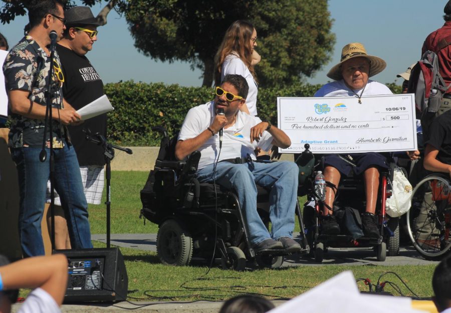 Humberto Gurmilan speaks to a crowd while presenting a grant on stage of Walk and Roll San Diego