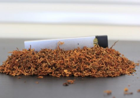 A JULL vaping device rests upon a mound of tobacco