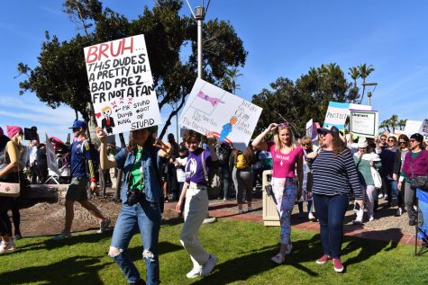 Women smiling and holding signs.