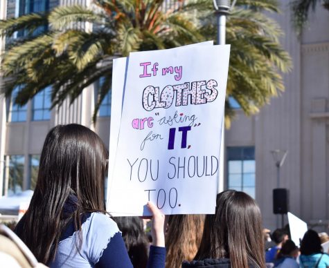 Women holding a sign that reads "If my clothes are asking for it you should too."