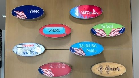 Presentation of I Voted stickers written multiple languages.