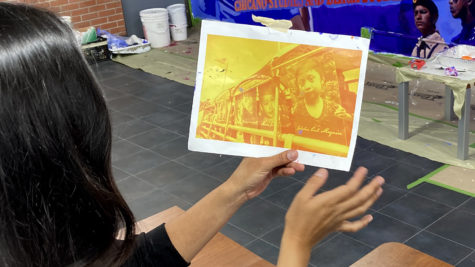 Artist Alicia Siu holds a photograph of Jakelin Caal Maquin she references in the City cafeteria mural