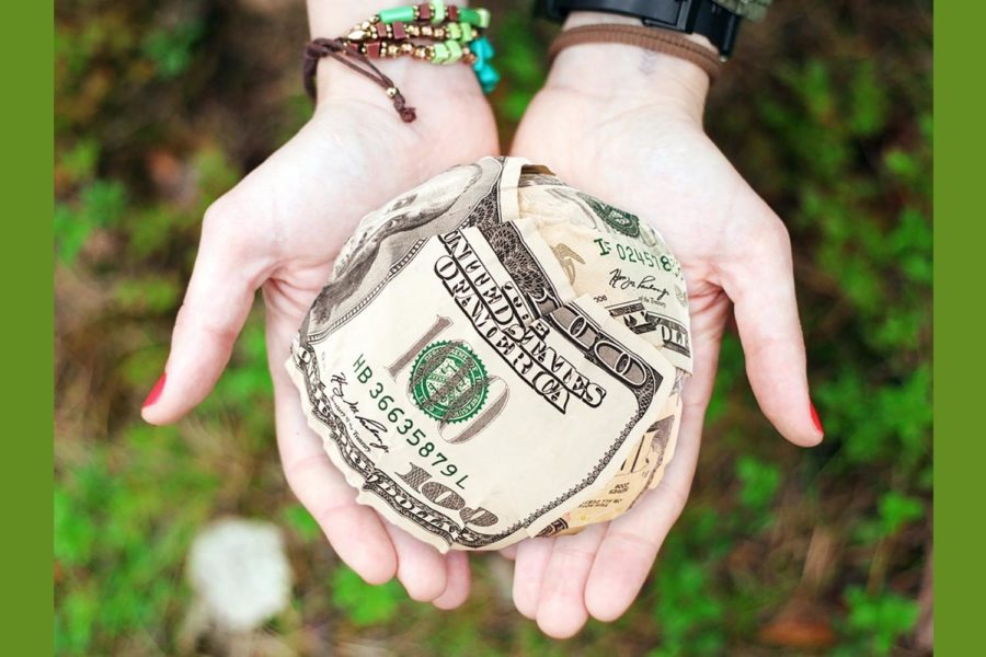 Two outstretched hands hold what appears to be hundred dollar bills formed into a ball