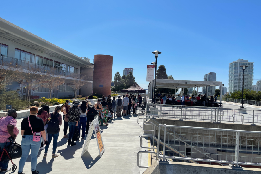 People gather in a line at the San Diego City College A building patio