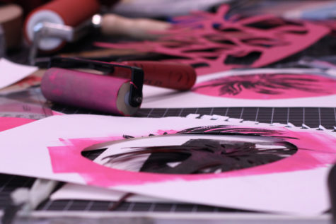 Ink rollers, cut paper and various pink and black prints are shown spread on a table.