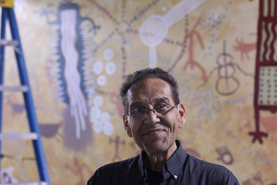 Kenneth Banks stands in front of the mural he designed in the AH Building garage at City College