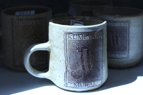 A mug with Kenneth Banks' "healing symbol" shape and the words "Kumeyaay Mural" on the front sits on a shelf in the City Gallery