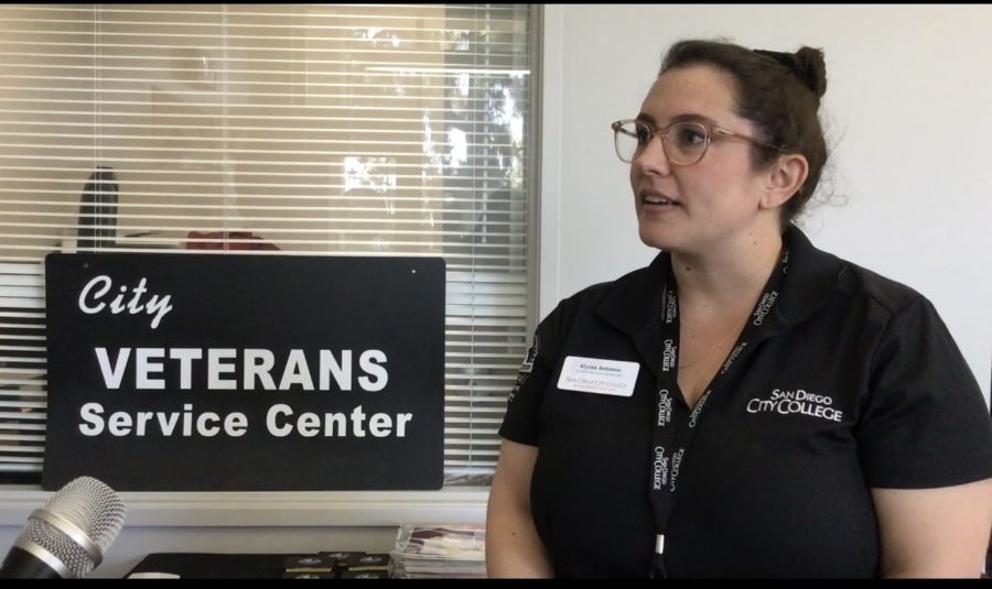 Student Service Technician Alyssa Antonio stands next to a City Veterans Service Center sign and does an interview with City Times reporters at the meet and greet.