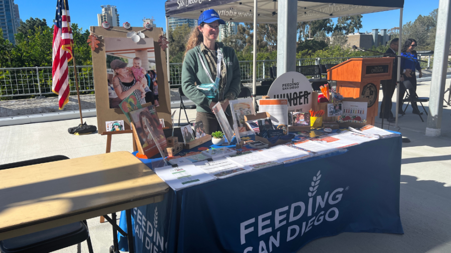 Michelle Berger, a representative of Feeding San Diego, stands in front of a table