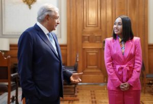 Katya Echazarreta dressed in a pink suit (right) speaks with Mexican President Andres Manuel Lopez Obrador dressed in a navy blue suit (left) in a large room in Mexico in 2022.
