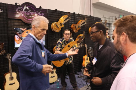 Rob Smith, left, showing students Bernard Clark, center right, and Rusty Dickson, right, how to play his custom guitars during the NAMM show at the Anaheim Convention Center