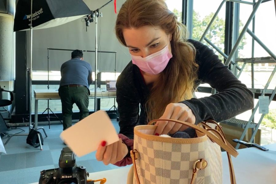 Graphic design student Ksenia La Russe touches up a handbag she is shooting for a project as professor Bradford Prairie rearranges another project under a big lightbox.