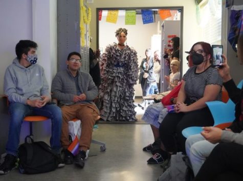 Drag performer stands at the doorway while students sit in chairs