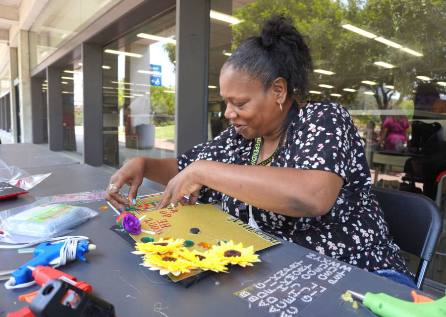 City College student Kelley Westley decorates her graduation cap with sunflowers and slogans like Wont He do it! and Never too late outside the bookstore on City campus.