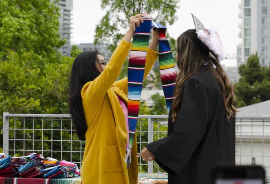 Professor Martinez places sash on graduate