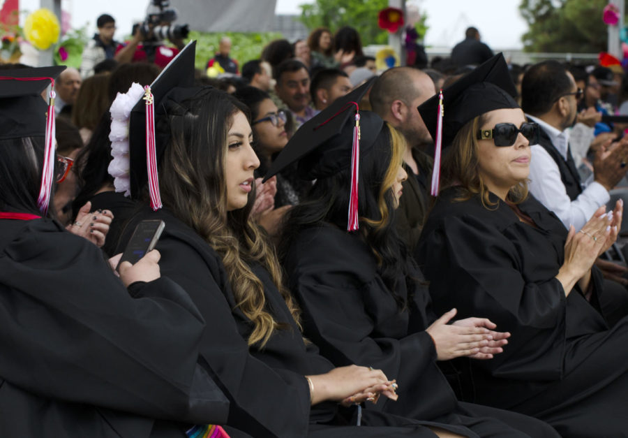 Seated graduates applaud classmates