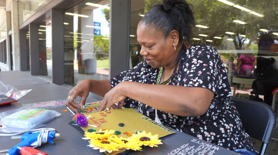 City College student Kelley Westley decorates her graduation cap with sunflowers and slogans like Wont He do it! and Never too late outside the bookstore on City campus.