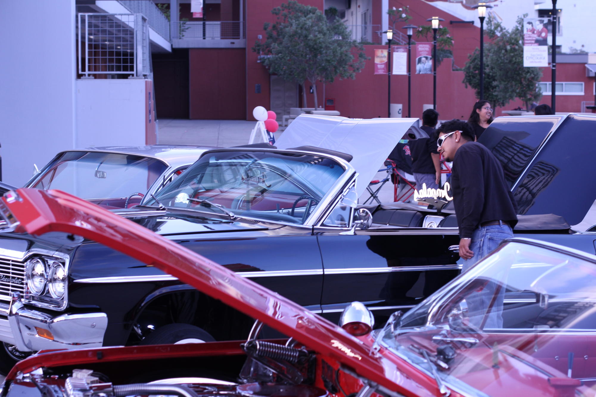 Gary Rodas, a former City College student, admires one of the Impala Car Club lowriders while attending the Noche de Familia event in support of his girlfriend, September 20, 2023. Photo by Keila Menjivar/City Times Media