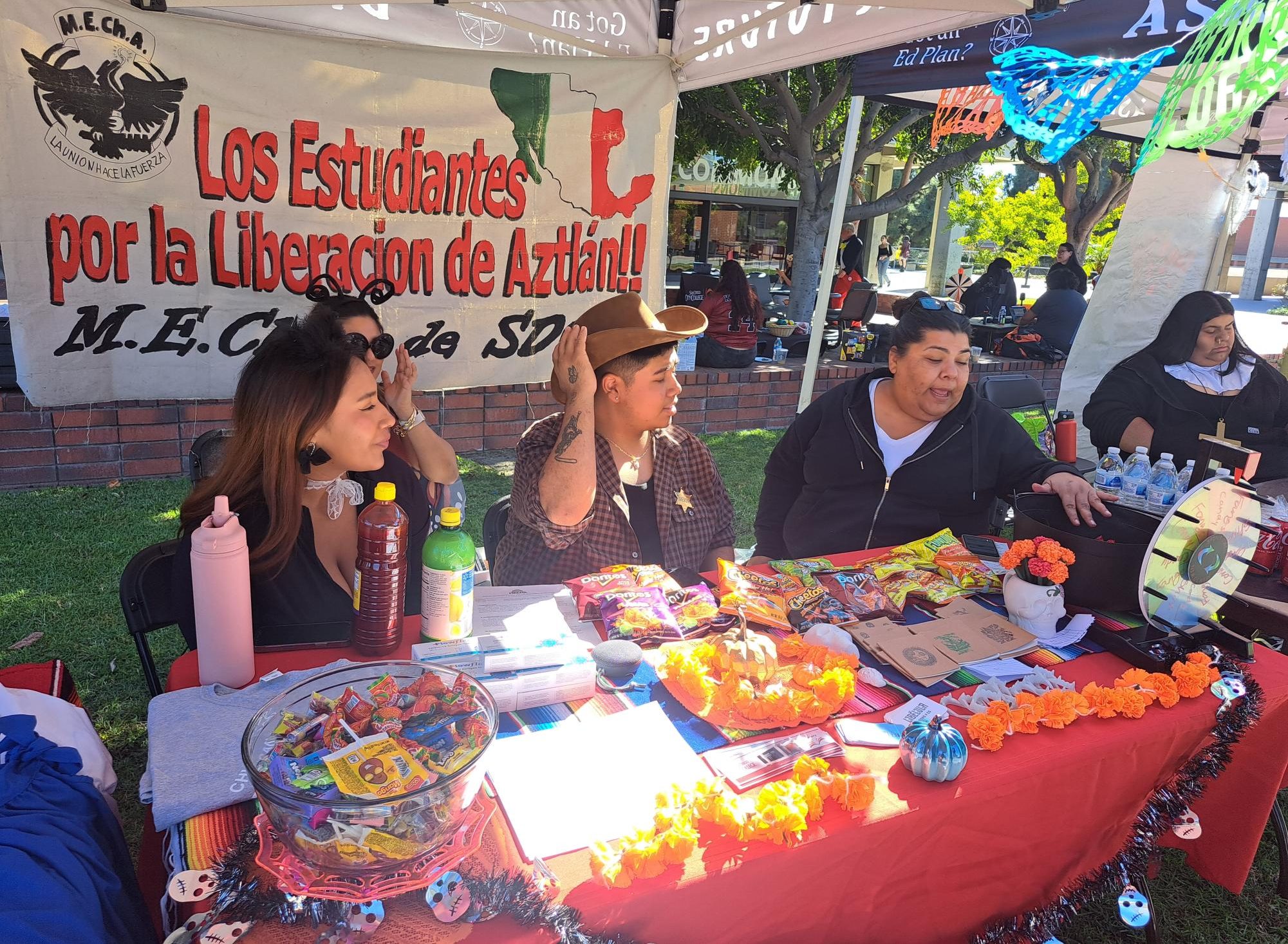 Vanessa Velez, center right, M.E.Ch.A. member and event organizer, explains what M.E.Ch.A. has to offer for students on who want to learn about being part of the Chicano community, Tuesday, Oct. 31, 2023. Photo by Luz Jaimes/City Times Media
