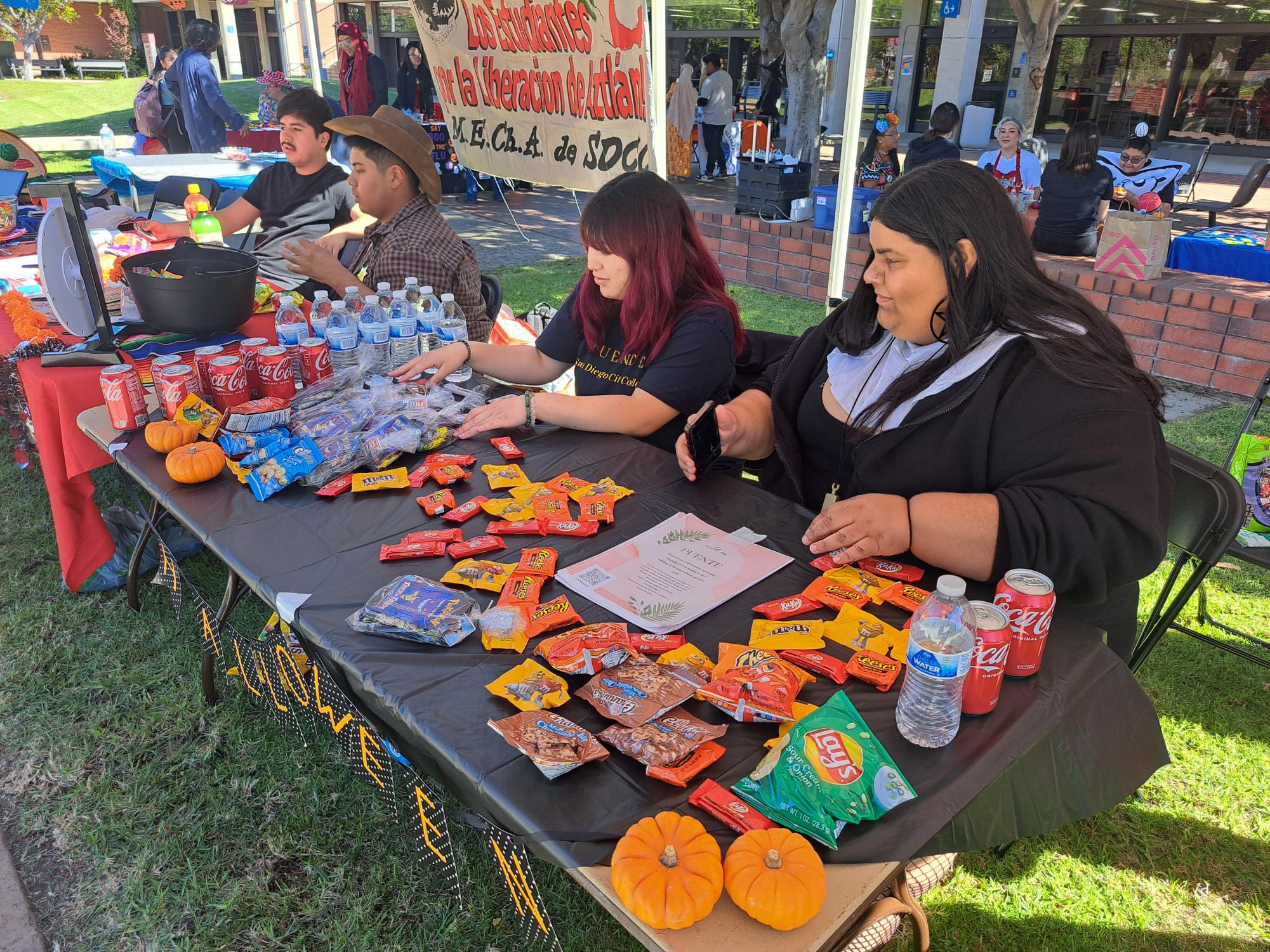 Puente Club President Isis Cabrera, center right, and club member Ramalda Zuniga, far right, finish setting their recruitment table for San Diego City College Club Rush, Tuesday, Oct. 31, 2023. Photo by Luz Jaimes/City Times Media