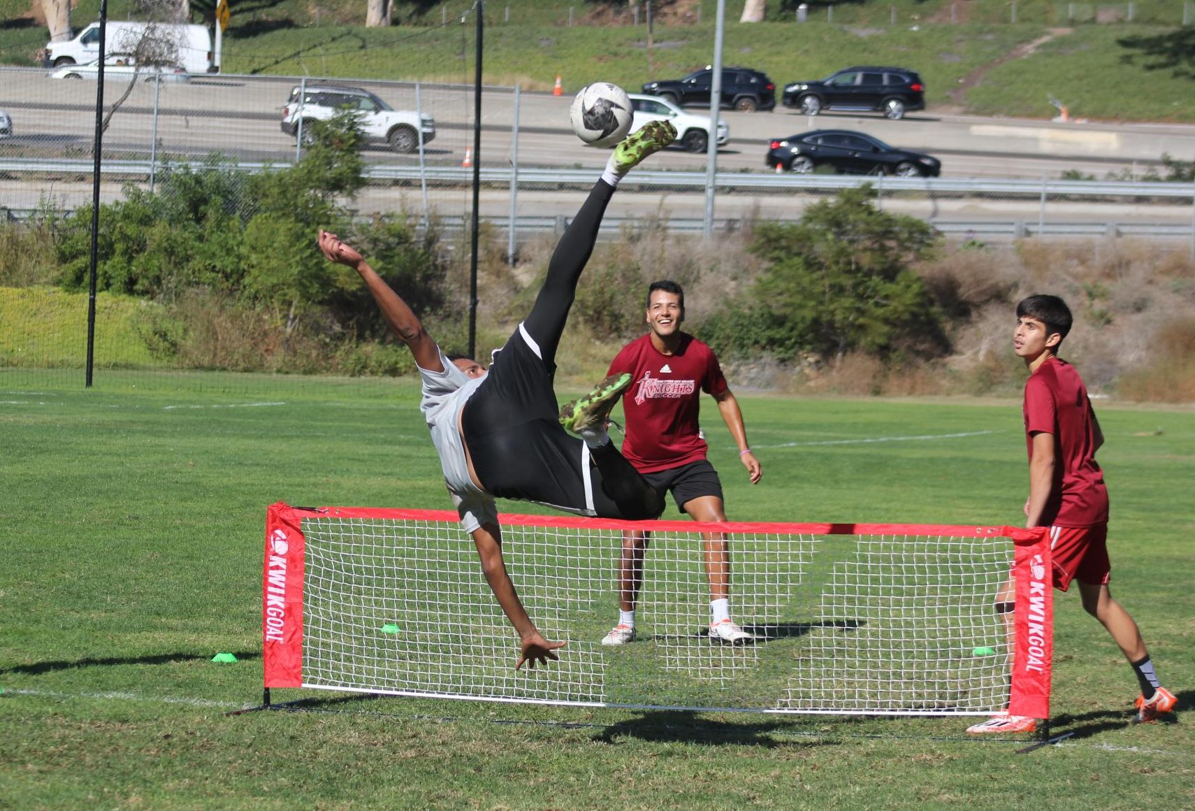 Sebastian Guillen practices a bicycle kick over a net during a practice drill with coach Alex Camacho, center, and teammate Justin Leal, right, at the City College soccer field, Nov. 8, 2023. Photo by Sean Monney/City Times Media