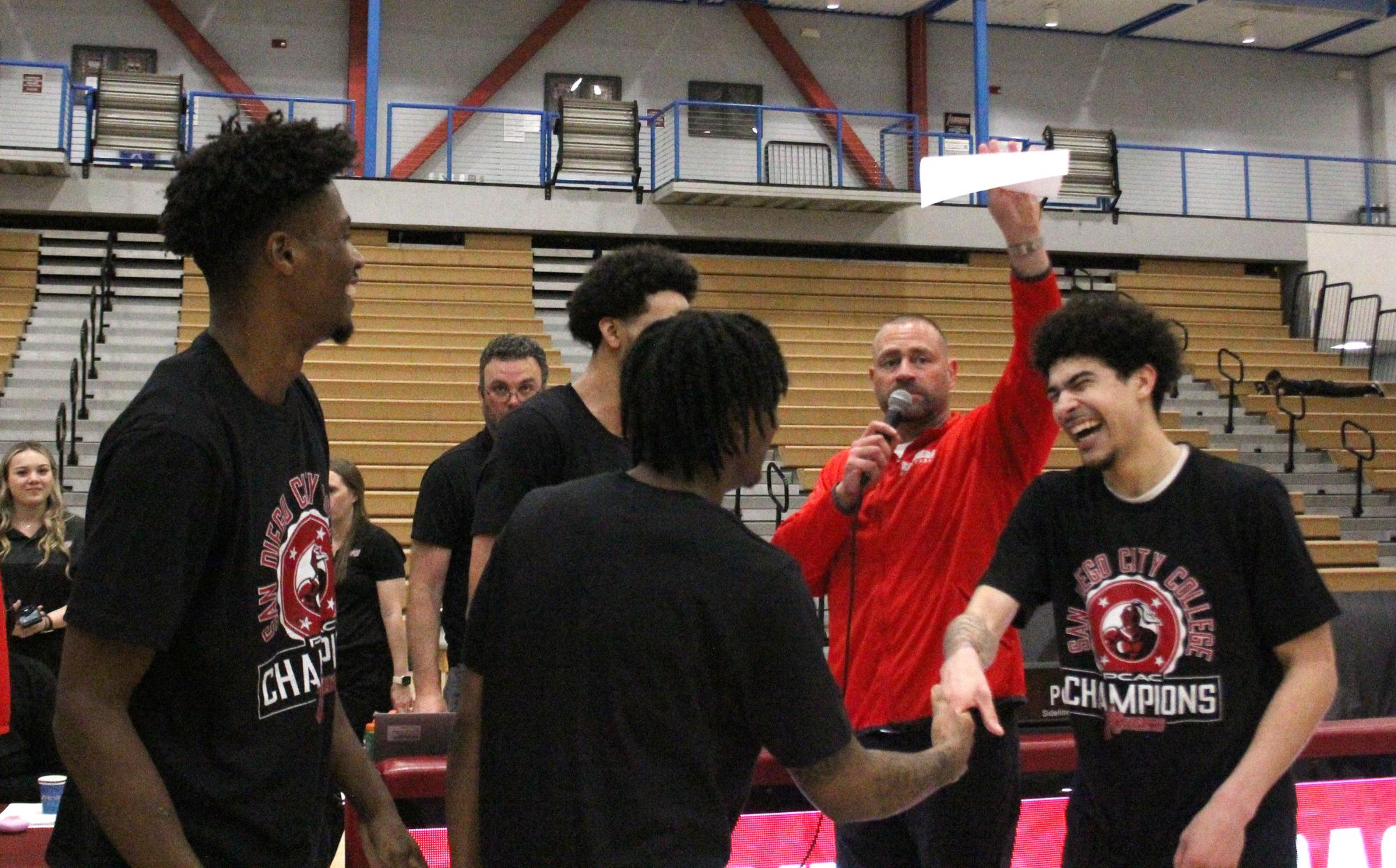 San Diego City College players, including Dillon Cubit, left, and Al Green, right, celebrate as Knights Head Coach Mitch Charlens delivers sophomore night recognitions after City’s 91-67 victory clinching sole possession of the Pacific Coast Athletic Conference championship at Harry West Gym, Feb. 23. 2024. Photo by Danny Straus/City Times Media