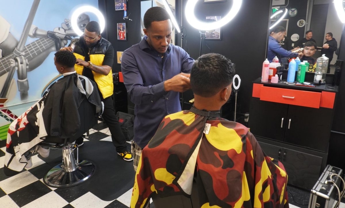 Barber Glenroy Drew, center right, gives Angel Sanchez, far right, a haircut during the Fresh Cutz barbershop grand opening in San Diego City College, April 23, 2024. Fresh Cutz aims to support male students to enroll in academic programs with academic and personal counseling at City College. Photo by Keila Menjivar Zamora/City Times Media