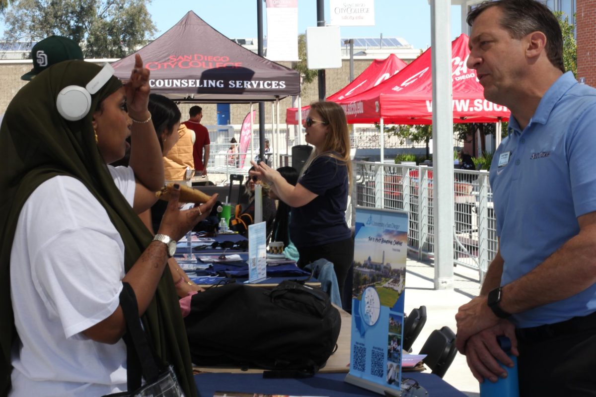 Filsan Jama, left, a biology major with UMOJA, discusses opportunities available at the University of San Diego with Scott Yahner, right, at the San Diego City College Spring 2024 Transfer Fair, Tuesday, April 16, 2024. Jama said she likes “to go around to different stations and get information so I can bring information back to the village(UMOJA).” Photo by Irie Caraballo/City Times Media
