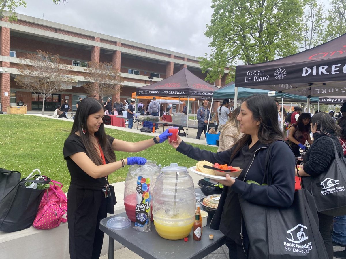 San Diego City College Basic Needs Coordinator Nydia Dominguez, left,  passes out juice to student Grecia Alcala, right, during a basic needs event, Tuesday, April 23, 2024. Photo by Samantha Griffen/City Times Media 