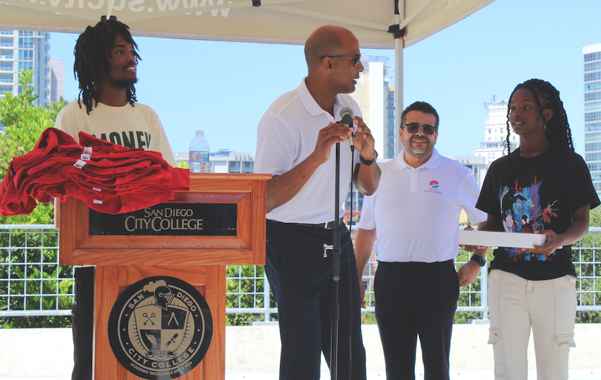 Students Keymuandre Abdallah, left, and Saika Didler, right, receive new laptops at the Black Excellence Meet and Greet Thursday, Aug. 29, 2024. Vice President of Administrative Services John Parker, with mic, introduces the winners with Vice President Student Services Marciano Perez, back, looking on. Photo By David J. Bohnet/City Times Media