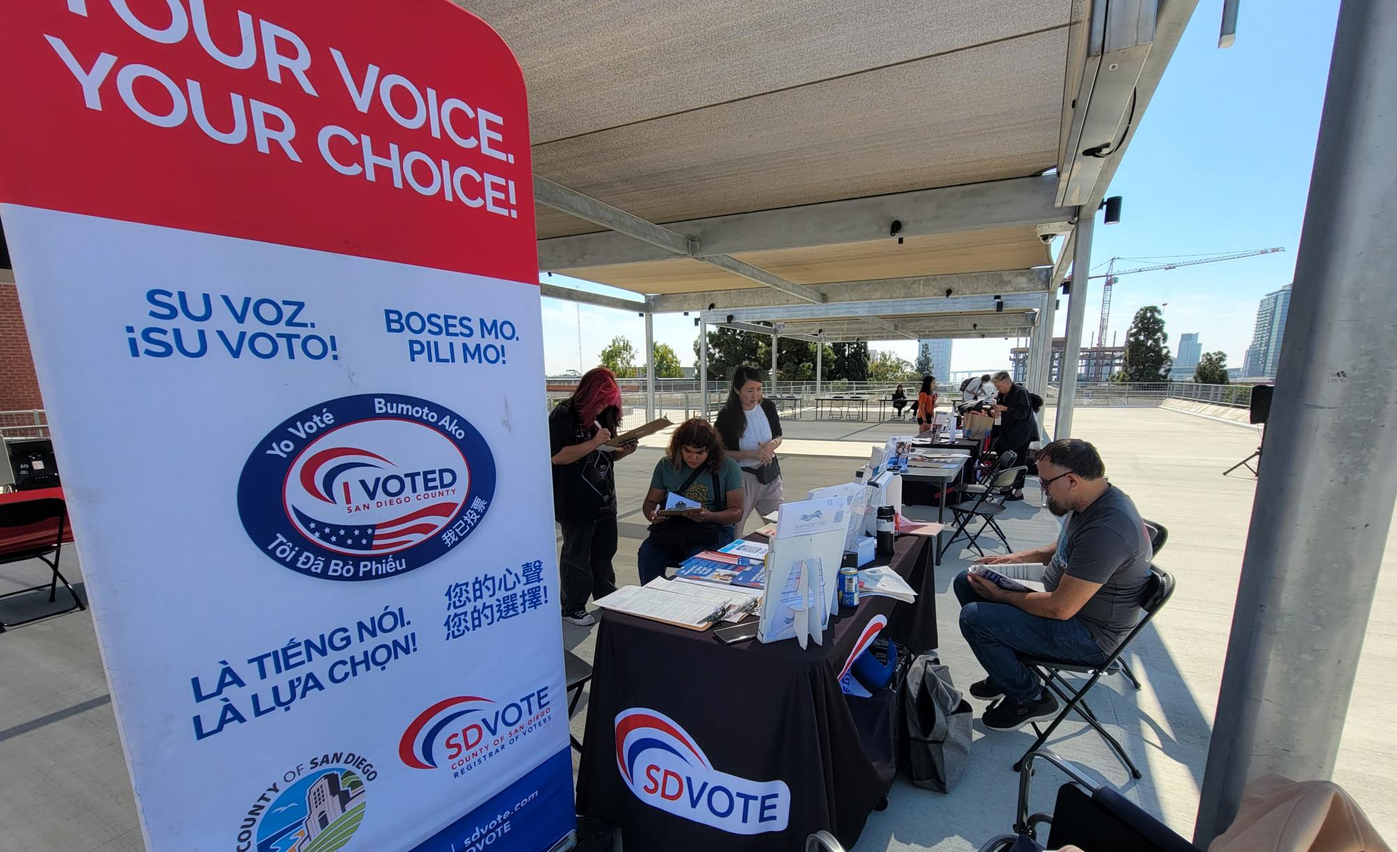 The County of San Diego Registrar of Voters group SDVOTE helping students register to vote by offering the needed paperwork and assisting them in filling it out at the Community Voter Registration Fair at City College on the A Building Patio, Oct. 8, 2024. Photo by Jordan Bell/City Times Media