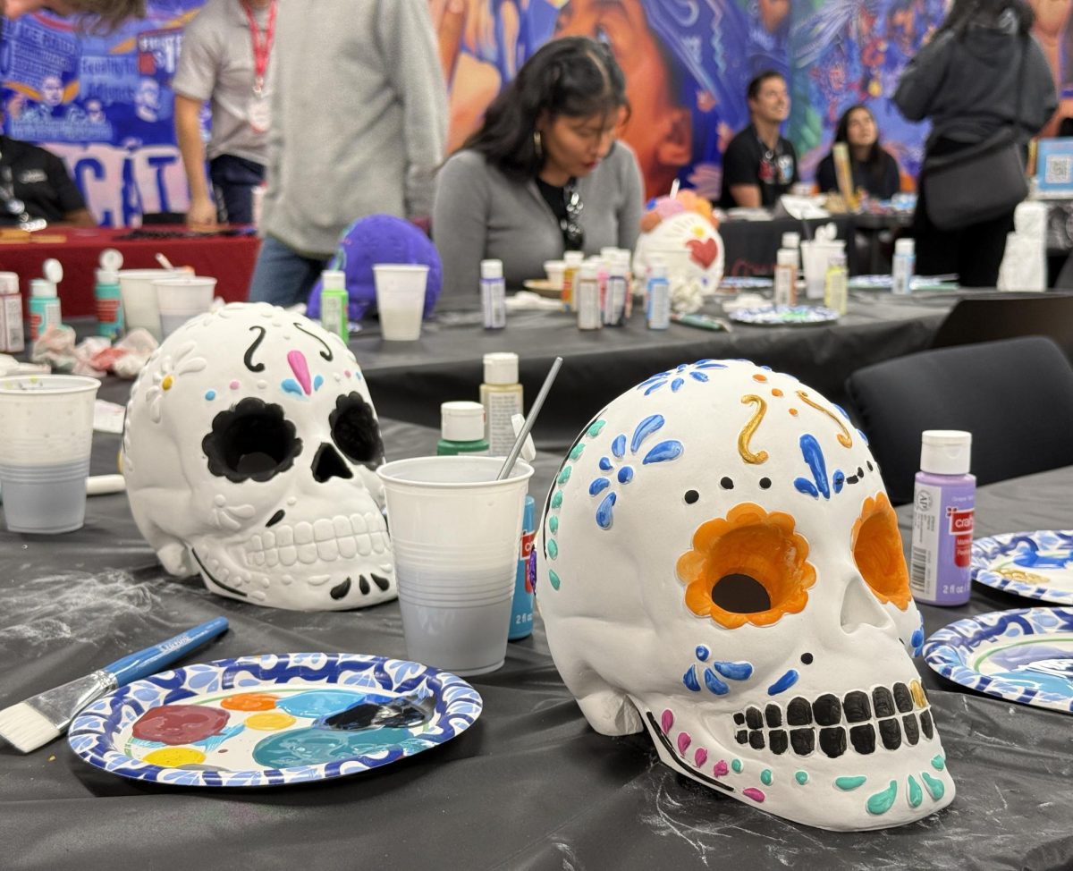 Jair Rodriguez, in gray, paints a sugar skull during the Día de los Muertos campus event Wednesday, Oct. 30, 2024. Completed skulls are later moved to the altar as an ofrenda. Photo by Luke Bradbury/City Times Media
