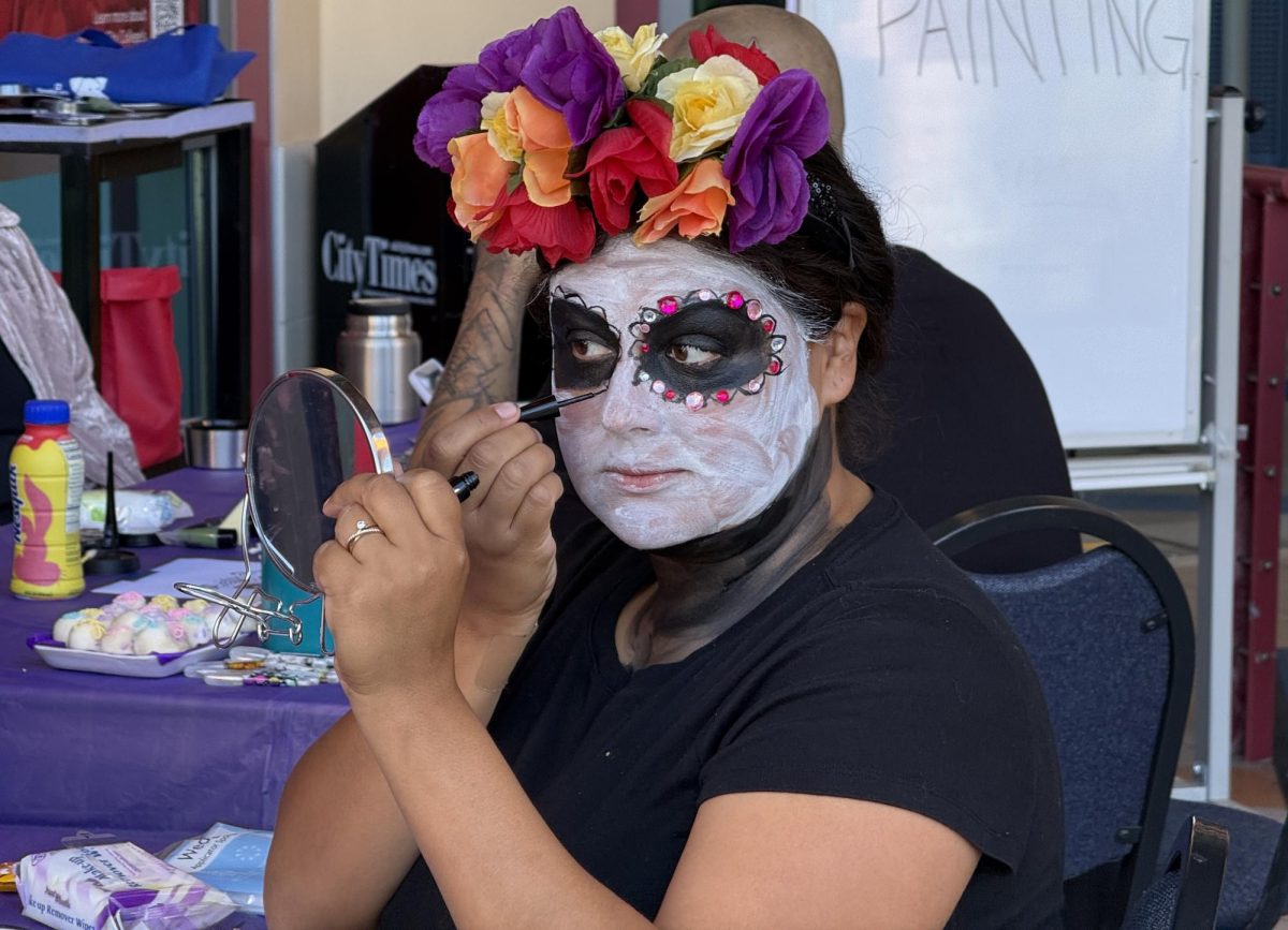 Priscilla Lomeli, a business finance major at San Diego City College, paints her face during the Día de los Muertos Festival at the City College Library Thursday, Oct. 31, 2024. Photo by Luke Bradbury/City Times Media