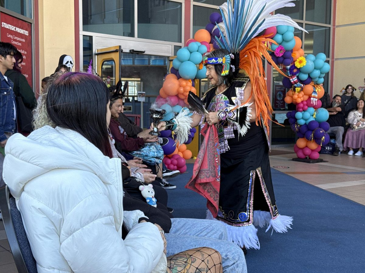 Beatrix Zamora, former counselor and dean for San Diego City College, wafts smoke over the viewers of Danza Mexicayotl before their performance at the Día de los Muertos Festival at the City College Library Thursday, Oct. 31, 2024. Photo by Luke Bradbury/City Times Media
