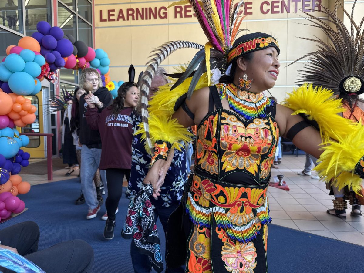 Velma Calvario, Chicano studies professor at San Diego City College, guides visitors through Danza Mexicayotl’s friendship dance during their performance at the Día de los Muertos Festival at the City College Library Thursday, Oct. 31, 2024. Photo by Luke Bradbury/City Times Media