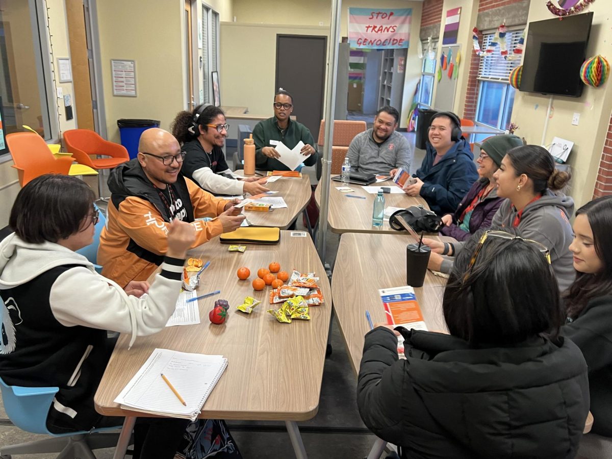 Both event coordinators sit at the end of a table, Noel Puga, left, and Jose Suarez Iniguez, right, surrounded by attendees of the Valentine’s Day event at the Pride Center Thursday, Feb. 13, 2025. Photo by Connor Jewett/City Times Media