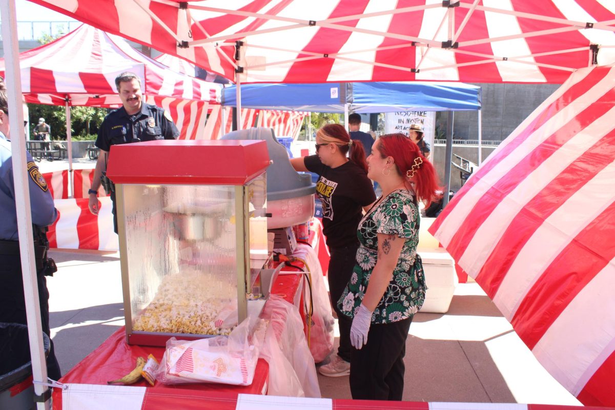 Nutrition student Mercedes Anderson, 27, left, and DSPS staff member Isadora Ruiz, 23, right, serves cotton candy and popcorn to students and police attending Club Rush Carnival, Tuesday, Sept. 9, 2025. Photo by Tresean Osgood/Co-Editor in Chief