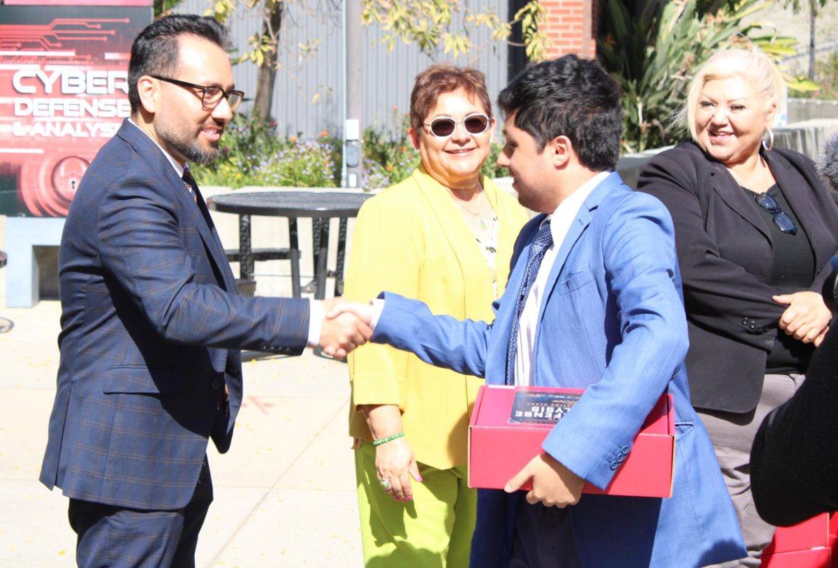 City College Dean Jesse Lopez, left, shakes hand with cybersecurity student Alexander Lopez, right, after he receives his graduation regalia at the AH quad, Tuesday, April 28, 2026. Lopez is part of the first cohort of bachelor's degree graduates in cyber defense and analysis at City College. Photo by Tresean Osgood/City Times Media